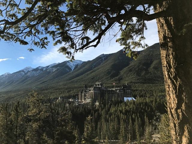 Fairmont Banff Springs Hotel, historic castle-like building nestled in Canadian Rockies with mountain peaks behind.