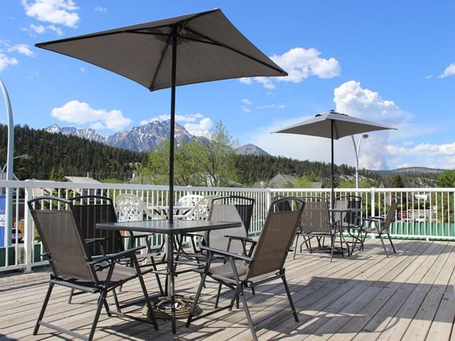 Outdoor patio at Filia Inn with tables, chairs, umbrellas, and mountain views.