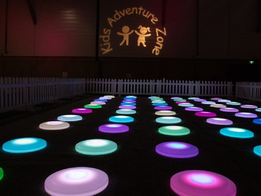 Colorful light-up stepping pads in the Kids Adventure Zone at Glow Christmas Festival.