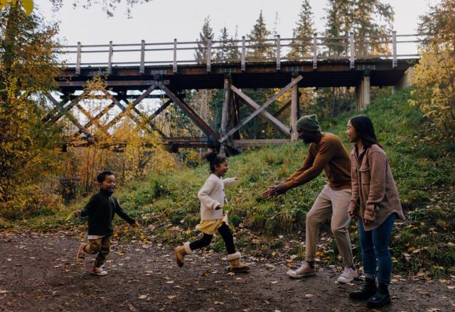 A mom and dad are joined by two smiling children near a bridge at Mill Creek Ravine.