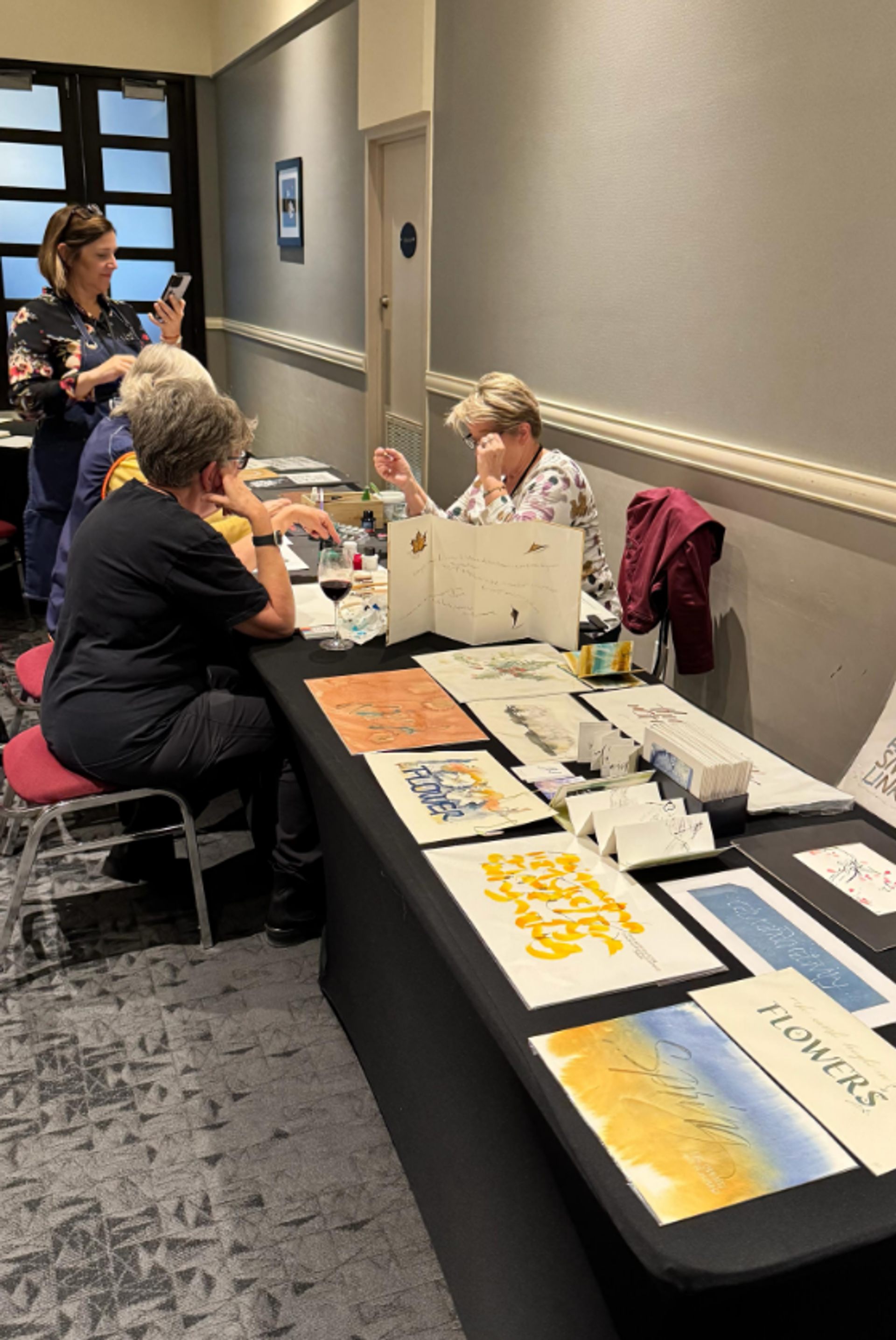 People create and display colourful artwork on tables in a conference room.