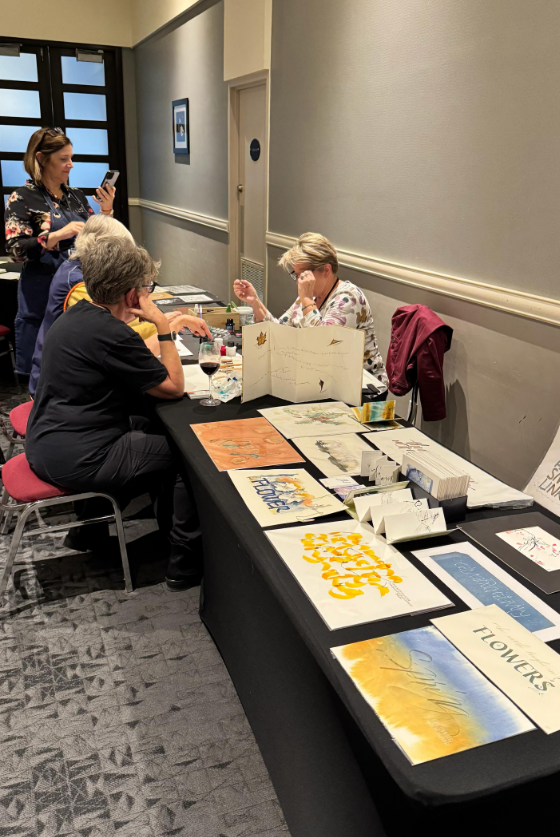 People create and display colourful artwork on tables in a conference room.