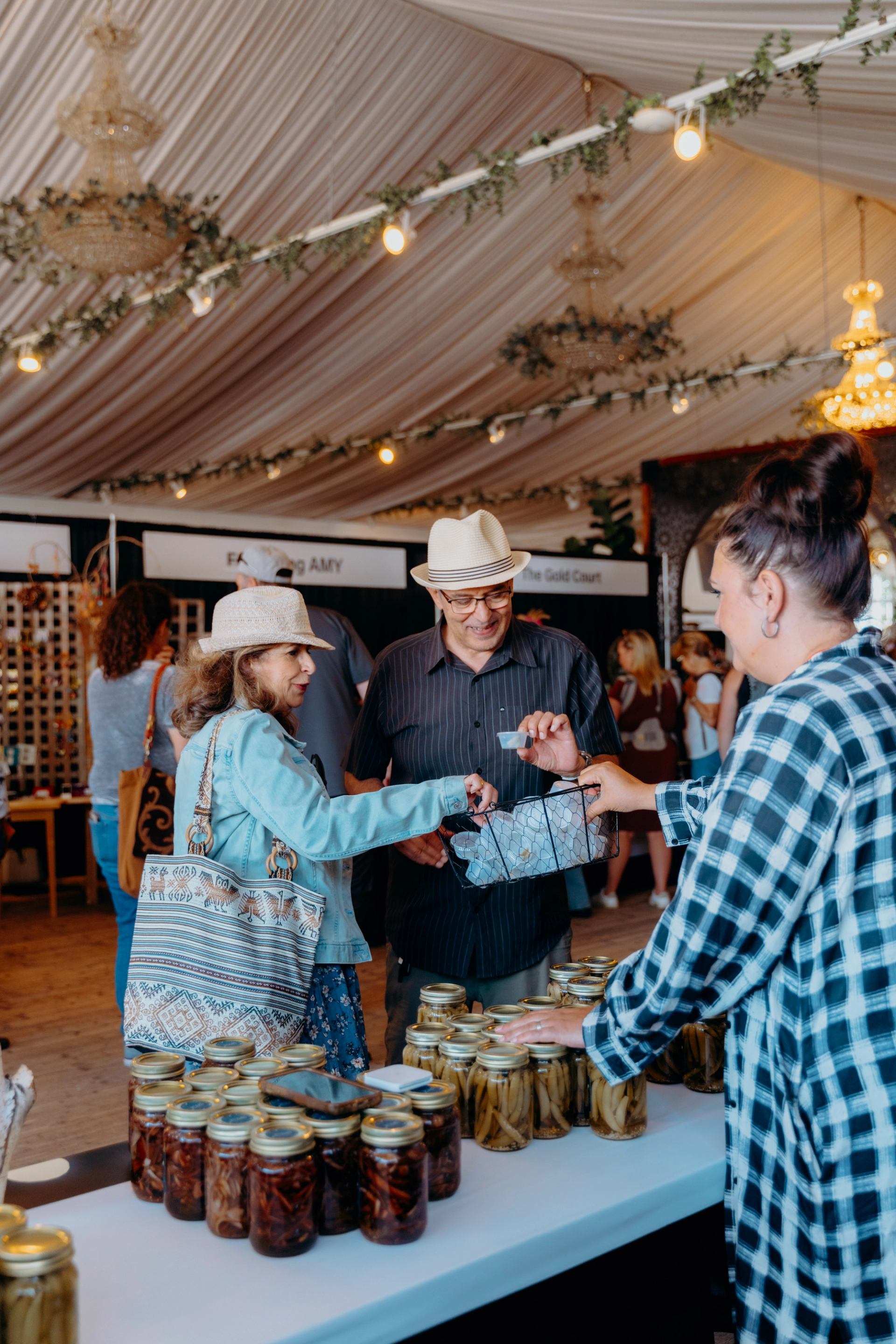 Attendees browse handmade goods and preserves inside a decorated vendor tent.