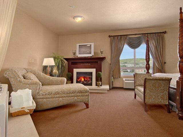 Cozy hotel room at Ramada Drumheller with fireplace and lounge seating.