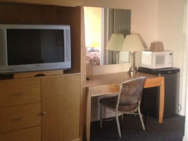 Hotel room desk with chair, TV, microwave, and mini fridge.