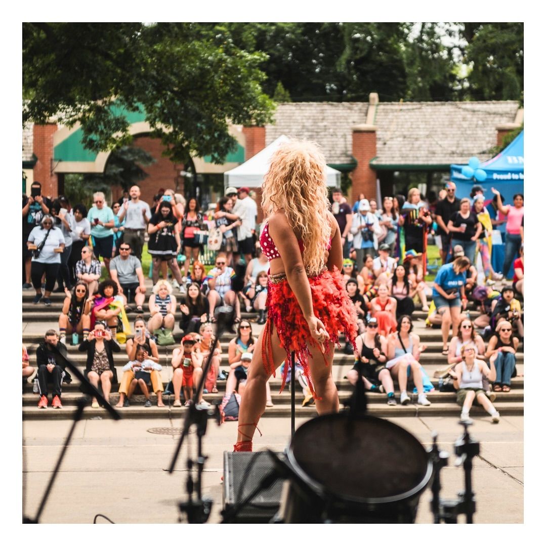 Performer on an outdoor stage facing a large crowd during Lethbridge Pride Fest.