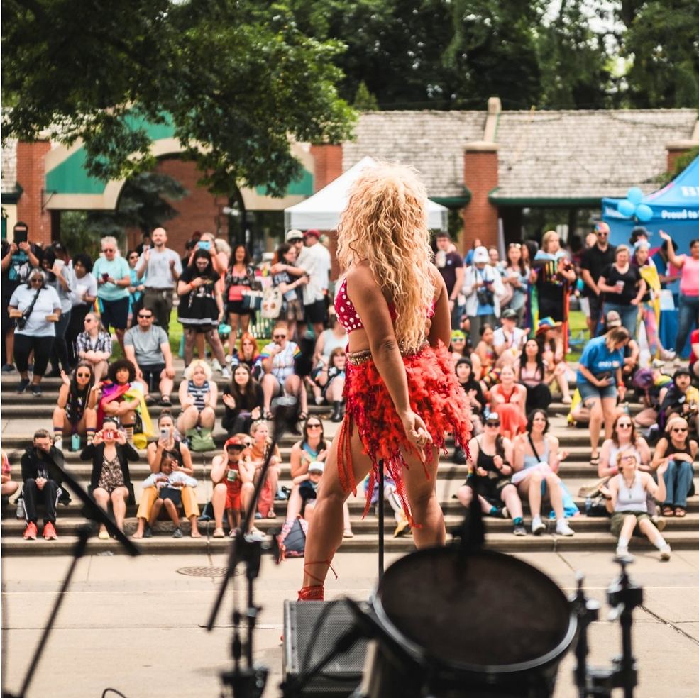 Performer on an outdoor stage facing a large crowd during Lethbridge Pride Fest.