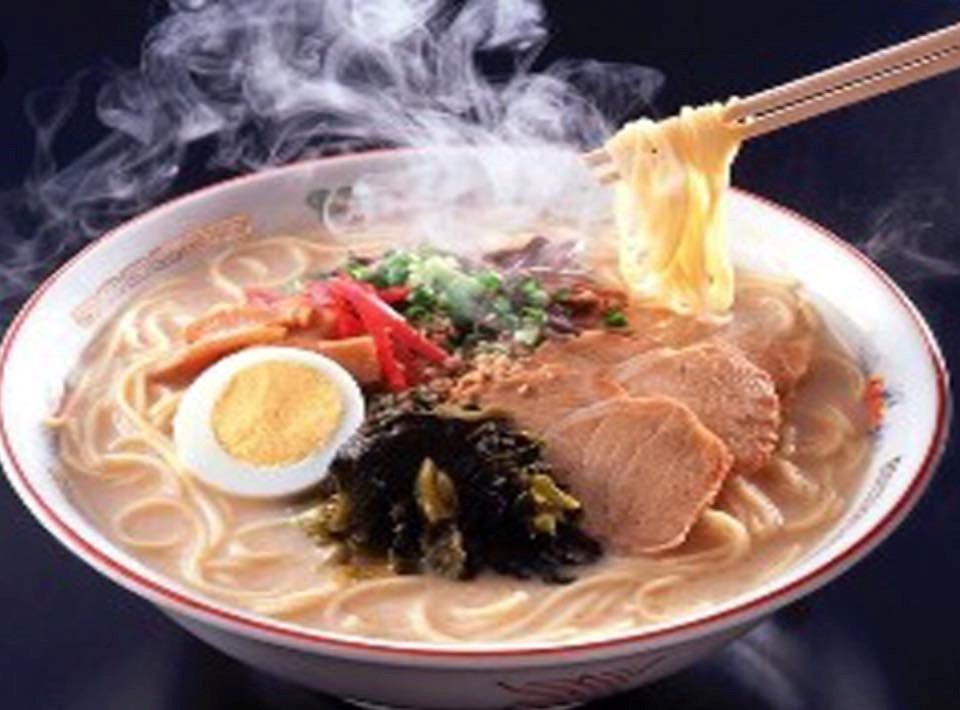 Bowl of ramen with noodles, egg, pork slices, and vegetables in broth