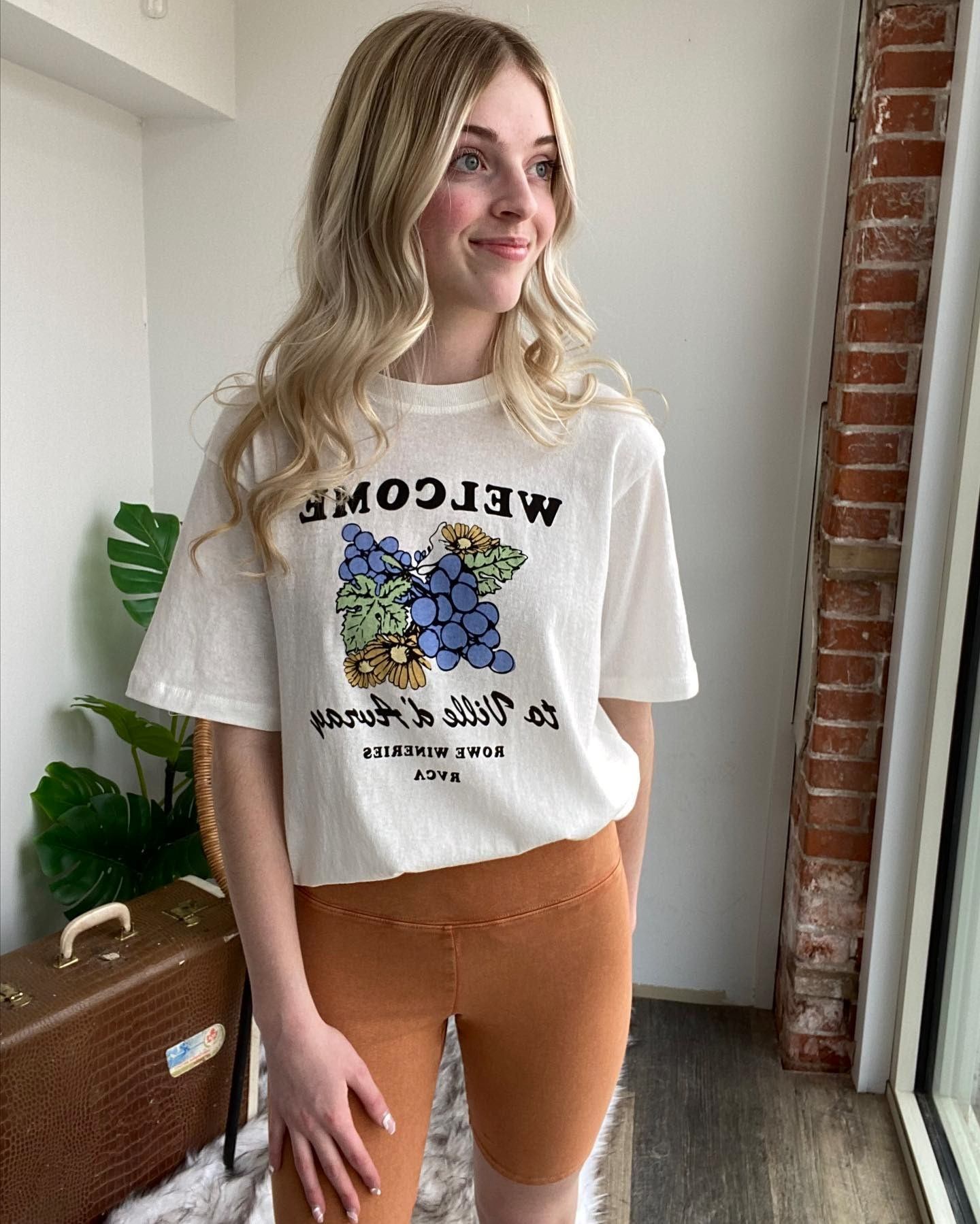 Person wearing a white T-shirt with blue grape graphic in a store interior.