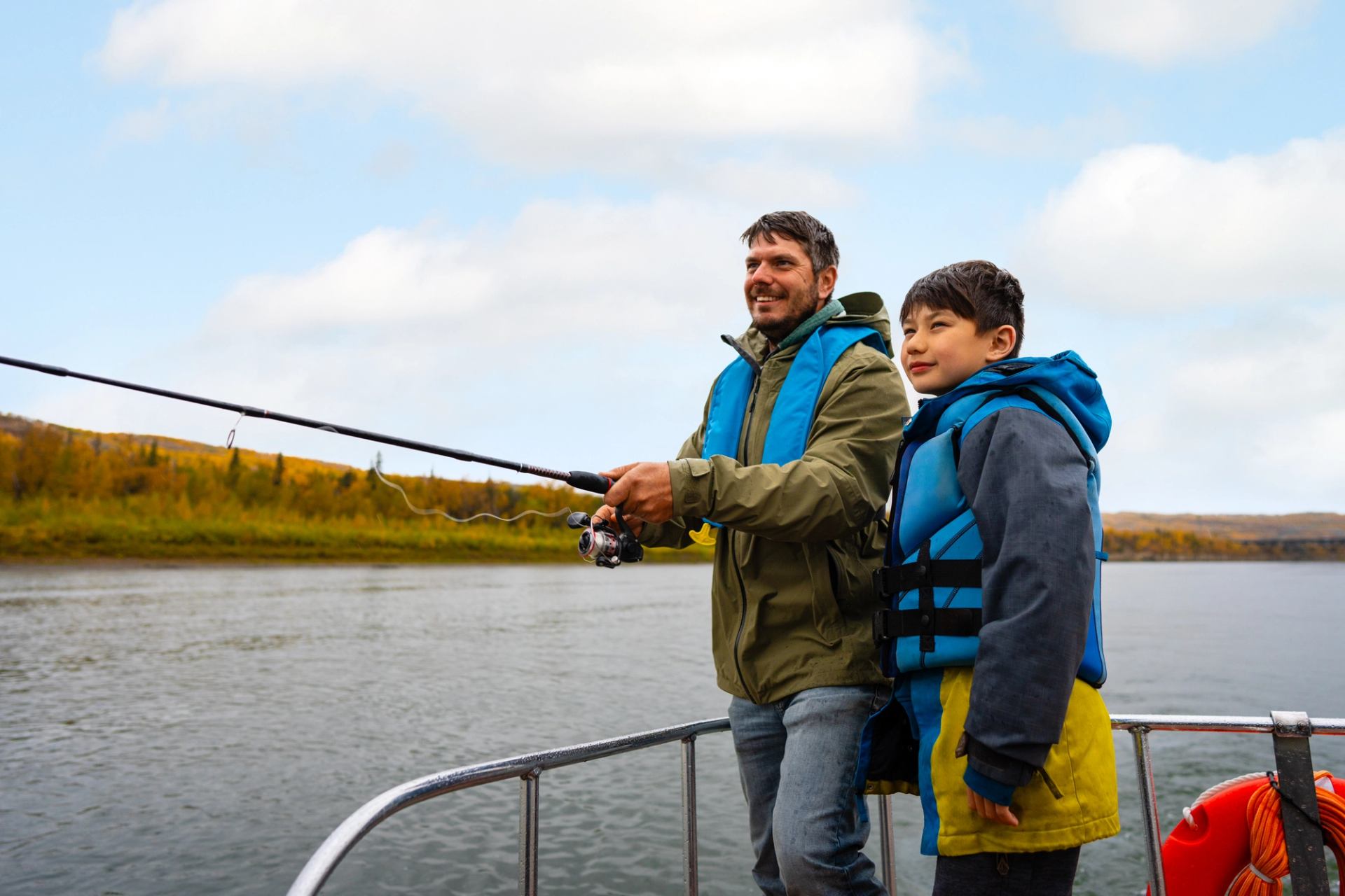 Two people fishing from a boat on calm water under a cloudy sky.
