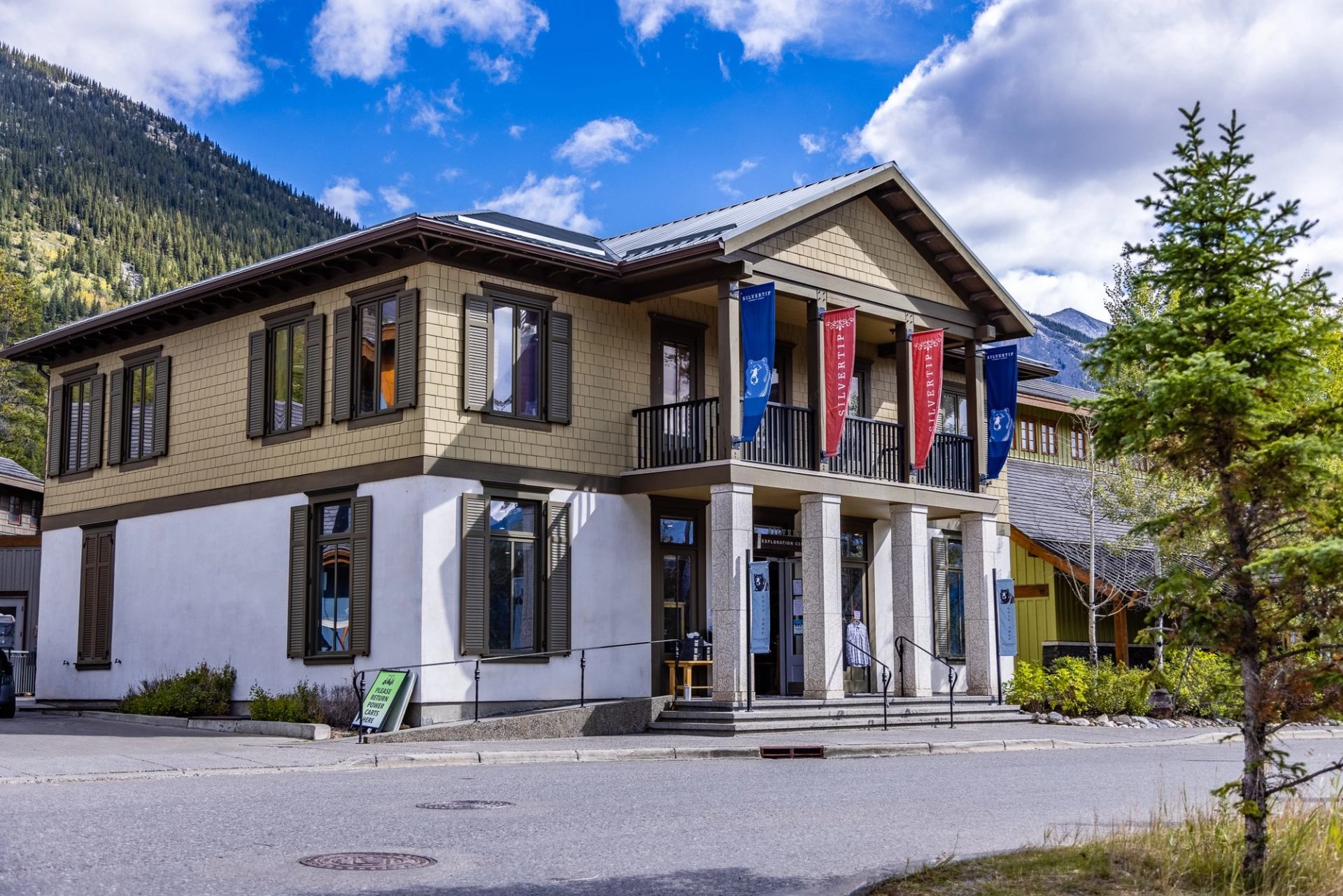 Two-story building with banners and mountain backdrop under a bright blue sky