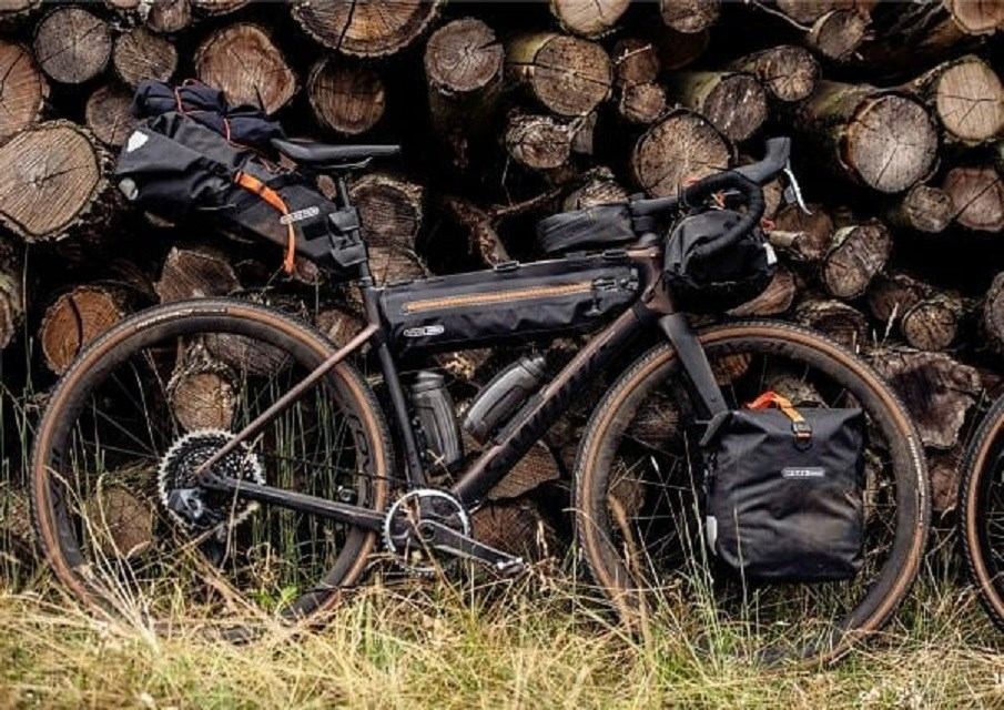 Touring bike with full gear parked in front of stacked logs.