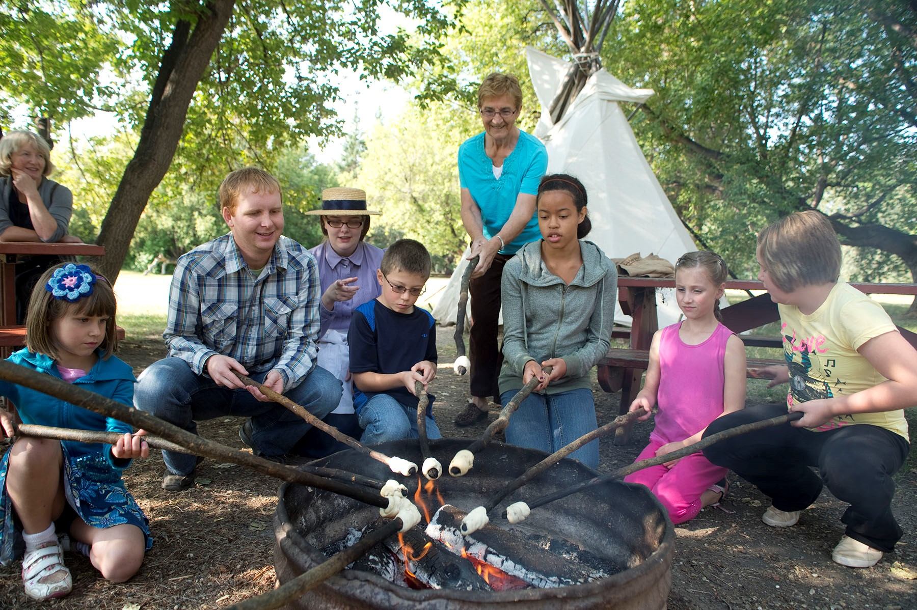 Group roasting marshmallows over a fire at Historic Dunvegan.