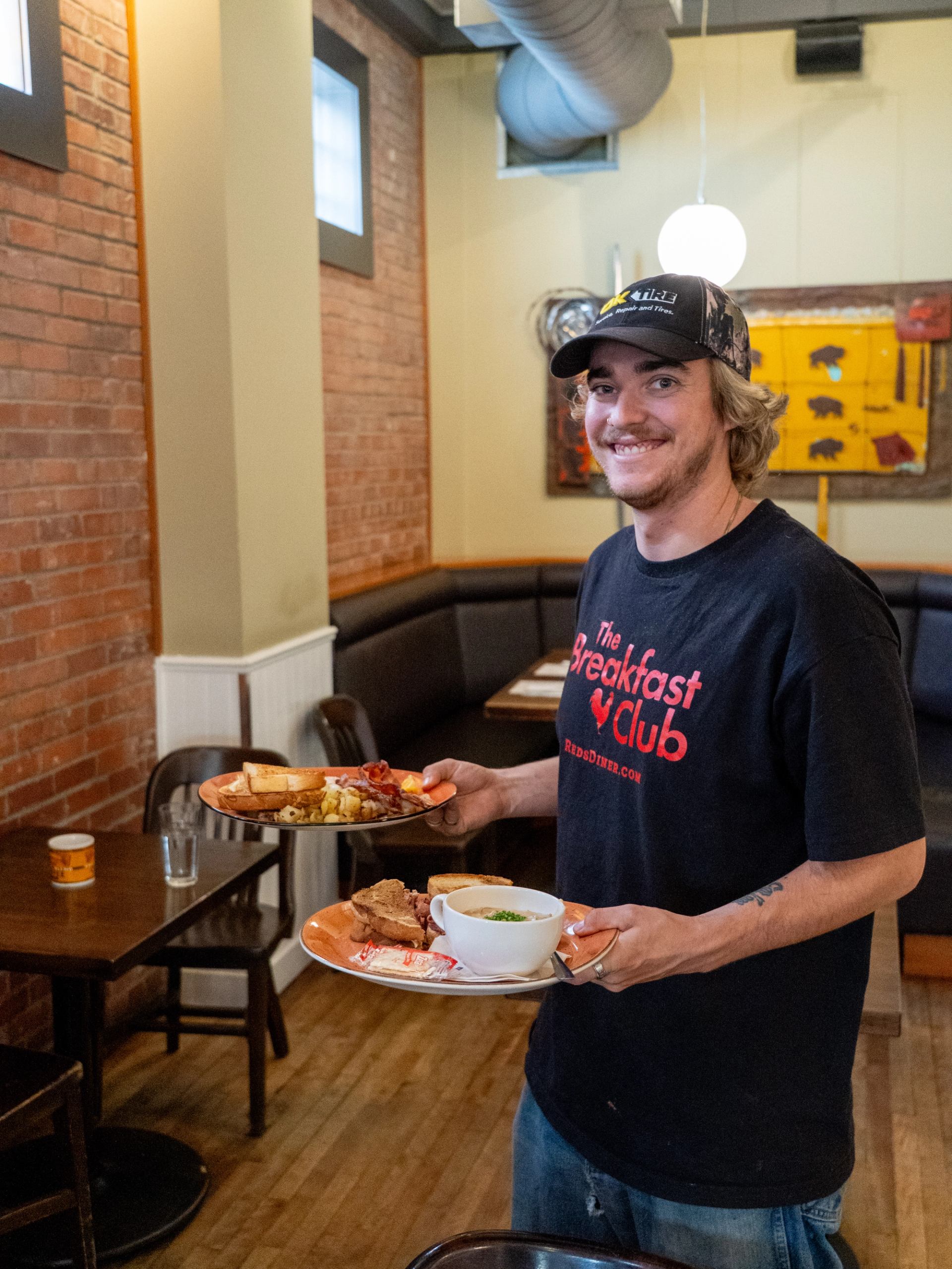 Restaurant server carries plates of breakfast food and soup through the dining room.