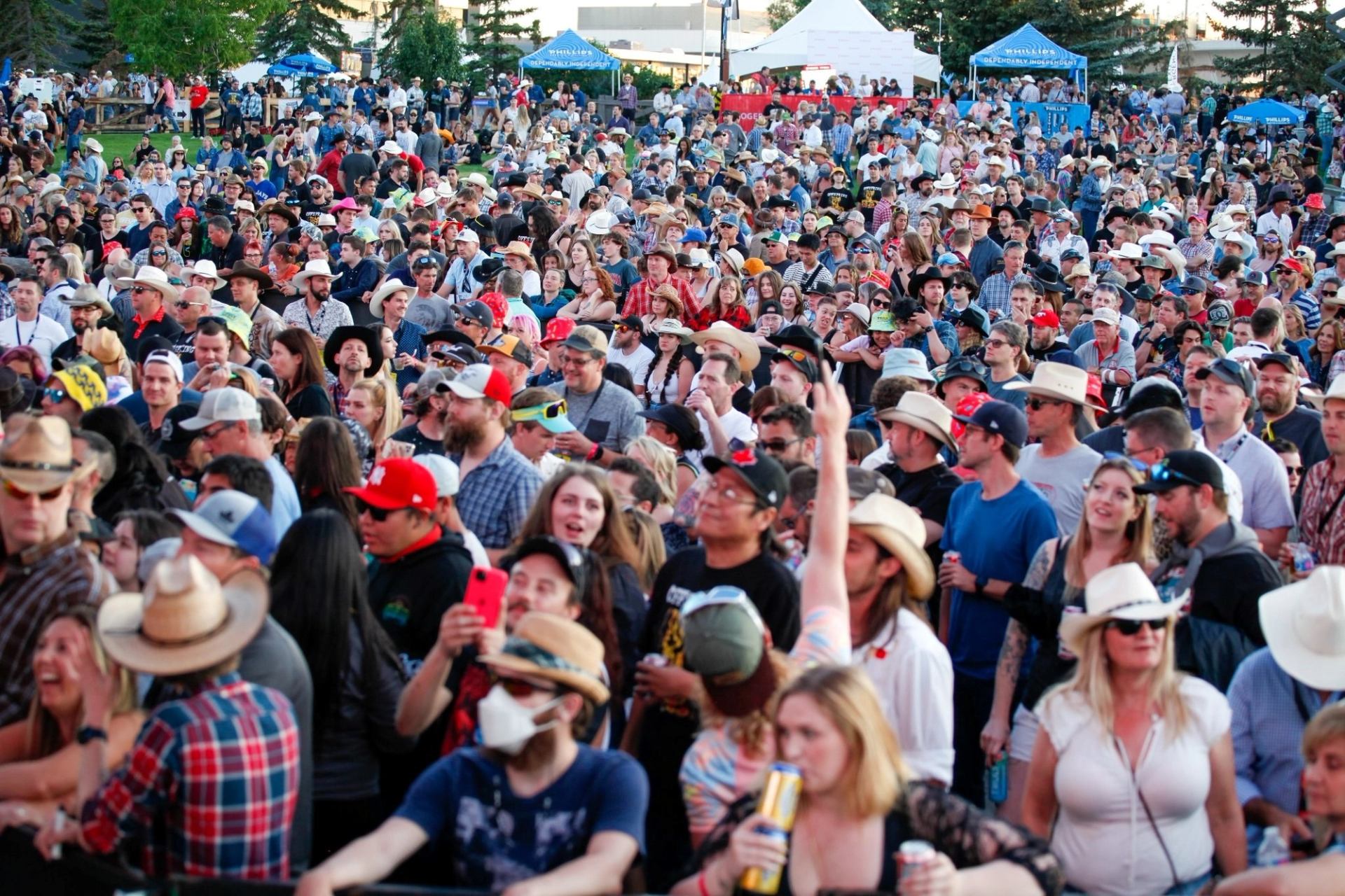 Large outdoor crowd in hats and casual clothes stands closely together at an event.