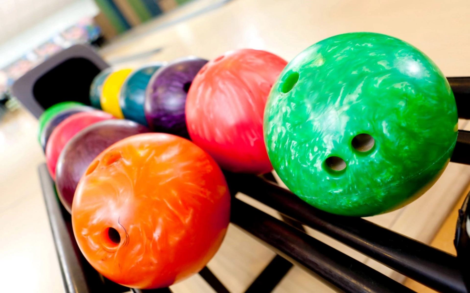 Bowling balls in green, orange, red, and purple on a lane at The Millennium Lanes.