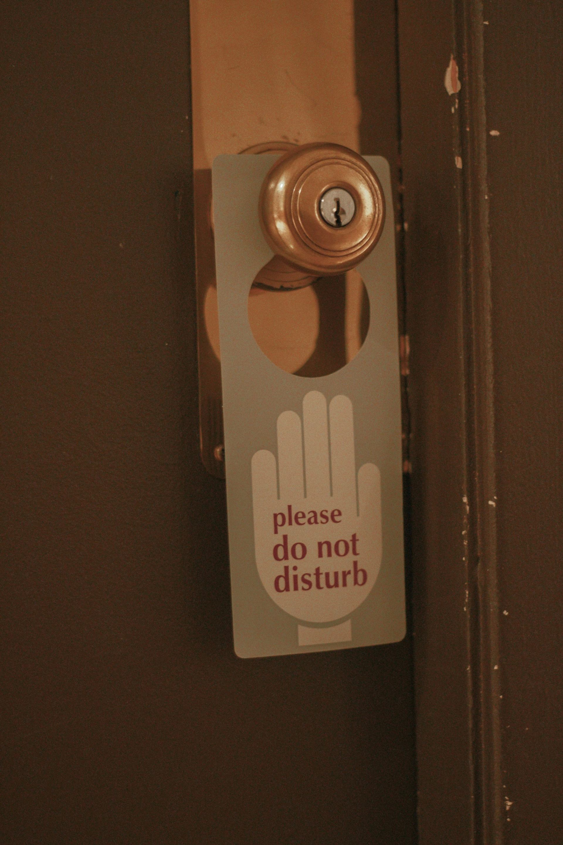 Hotel door knob with "please do not disturb" sign in red and white lettering.