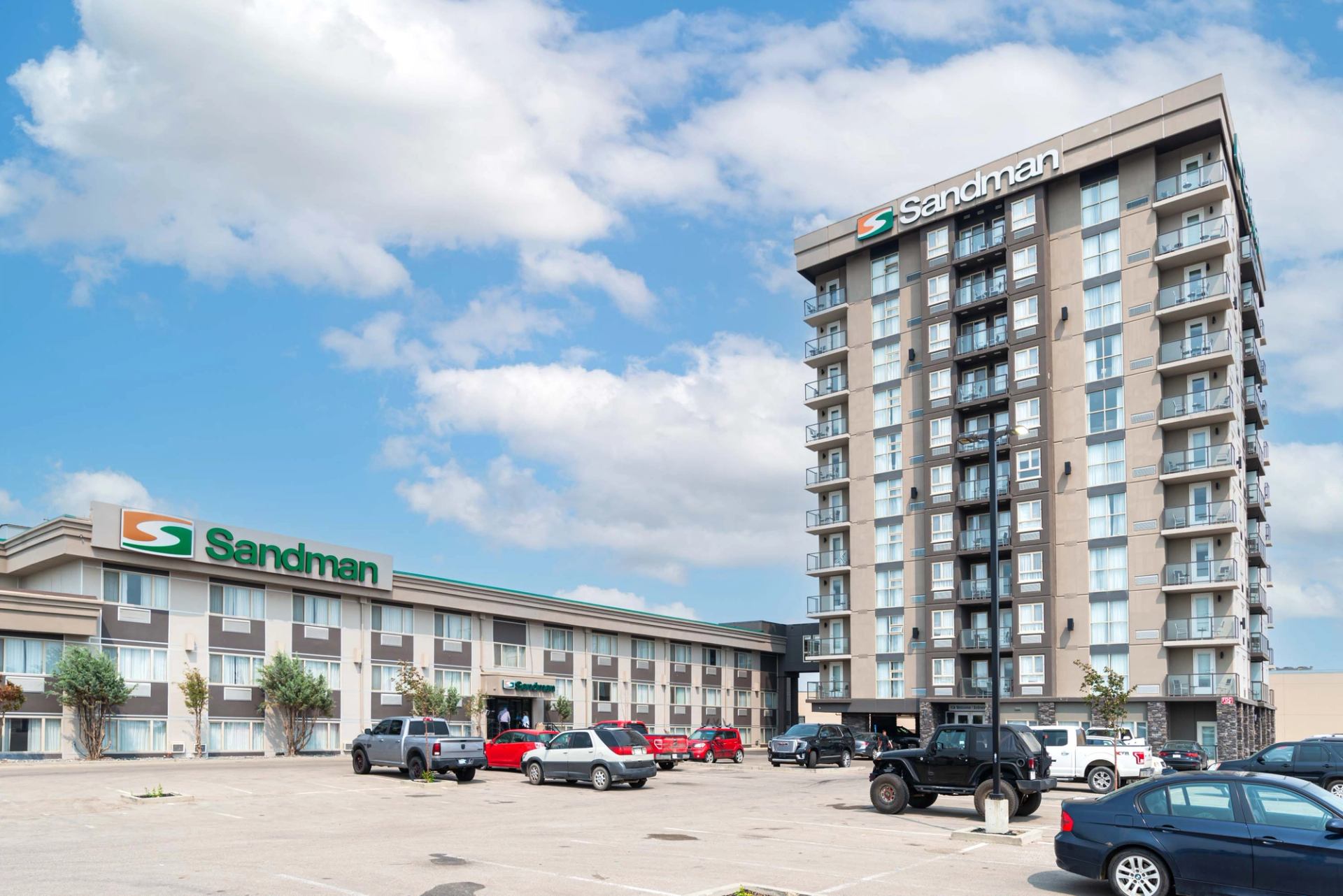 Exterior view of Sandman Hotel & Suites Edmonton West with parking and tall tower.