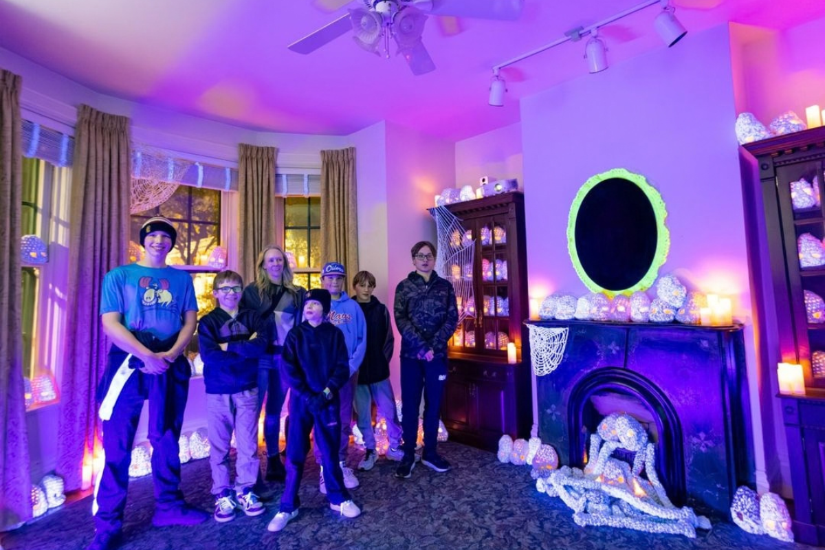 Group poses in a purple-lit room decorated with glowing sculptures and cobwebs.