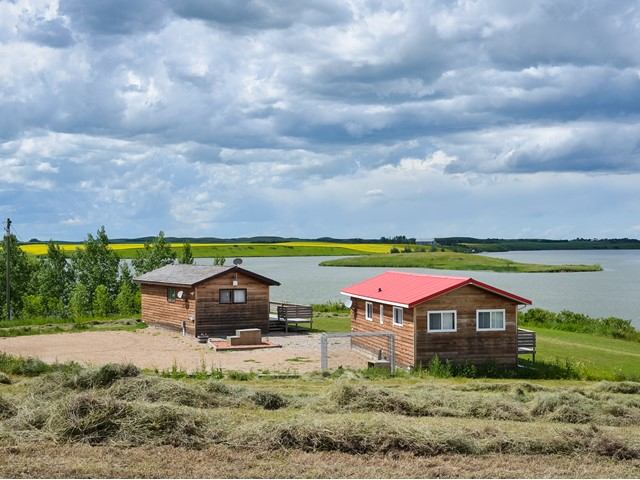 Two rustic cabins by a serene lake under a cloudy sky at Fox Lake Retreat.