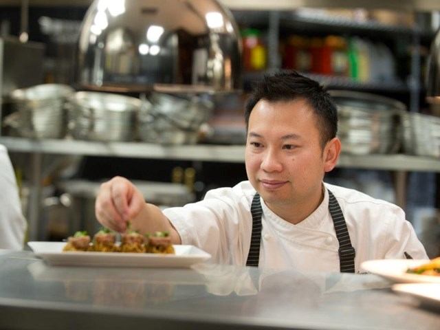 Chef garnishing a dish in a professional kitchen with focused precision.