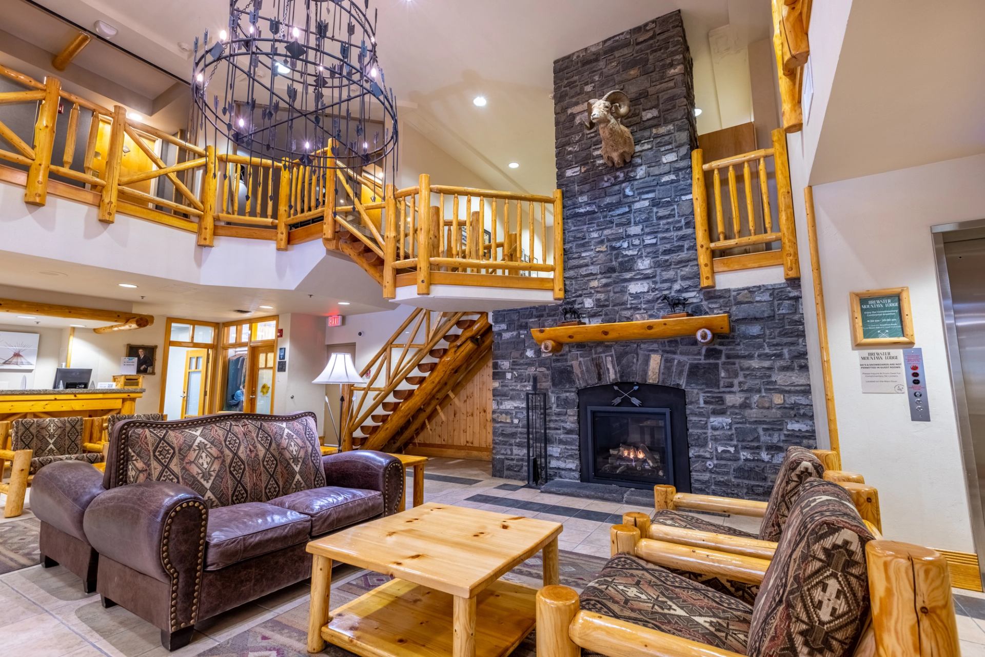 Rustic lodge living room with stone fireplace, leather seating, and wood décor.