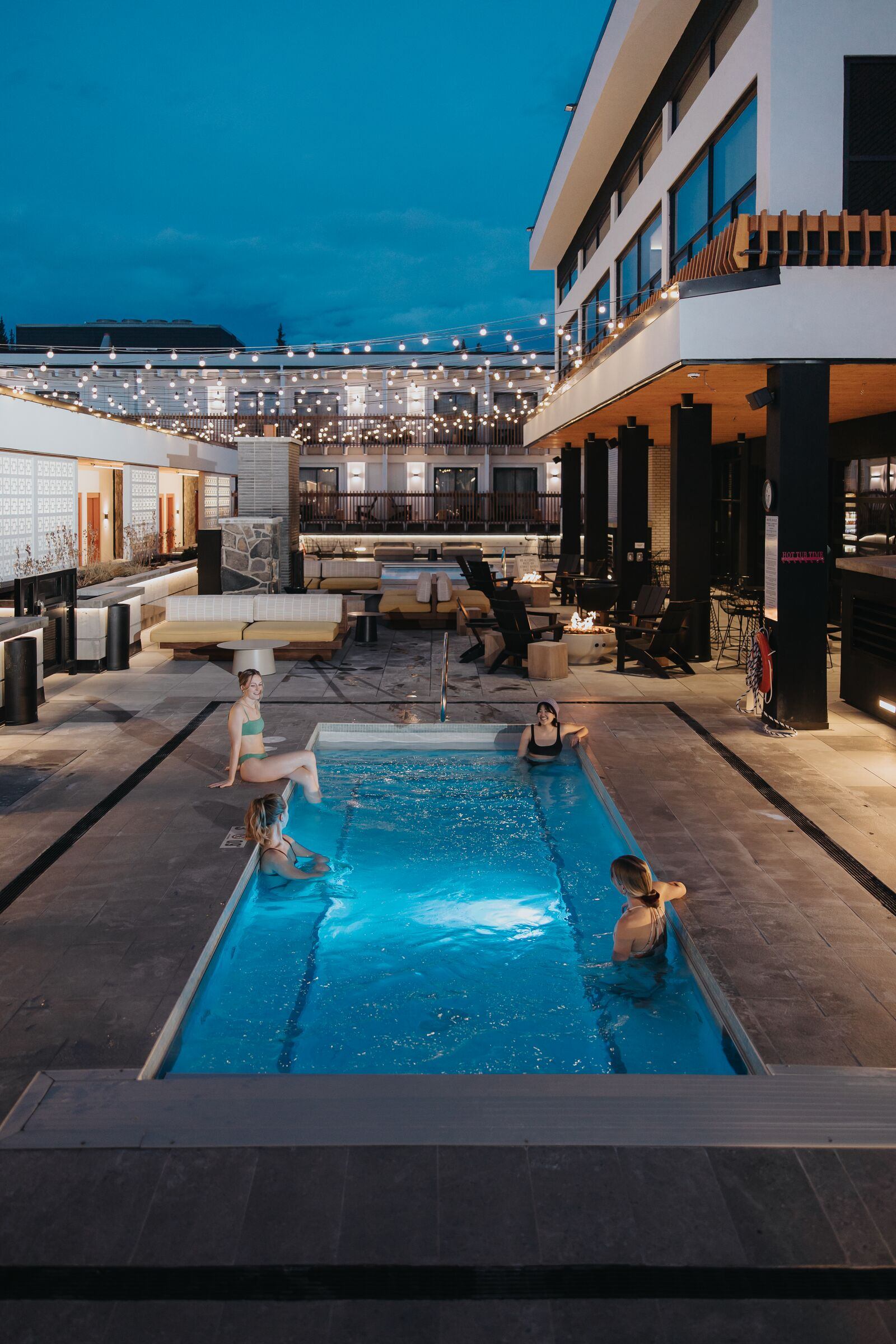 Four friends enjoying the outdoor pool at Moxy Hotel in Banff.