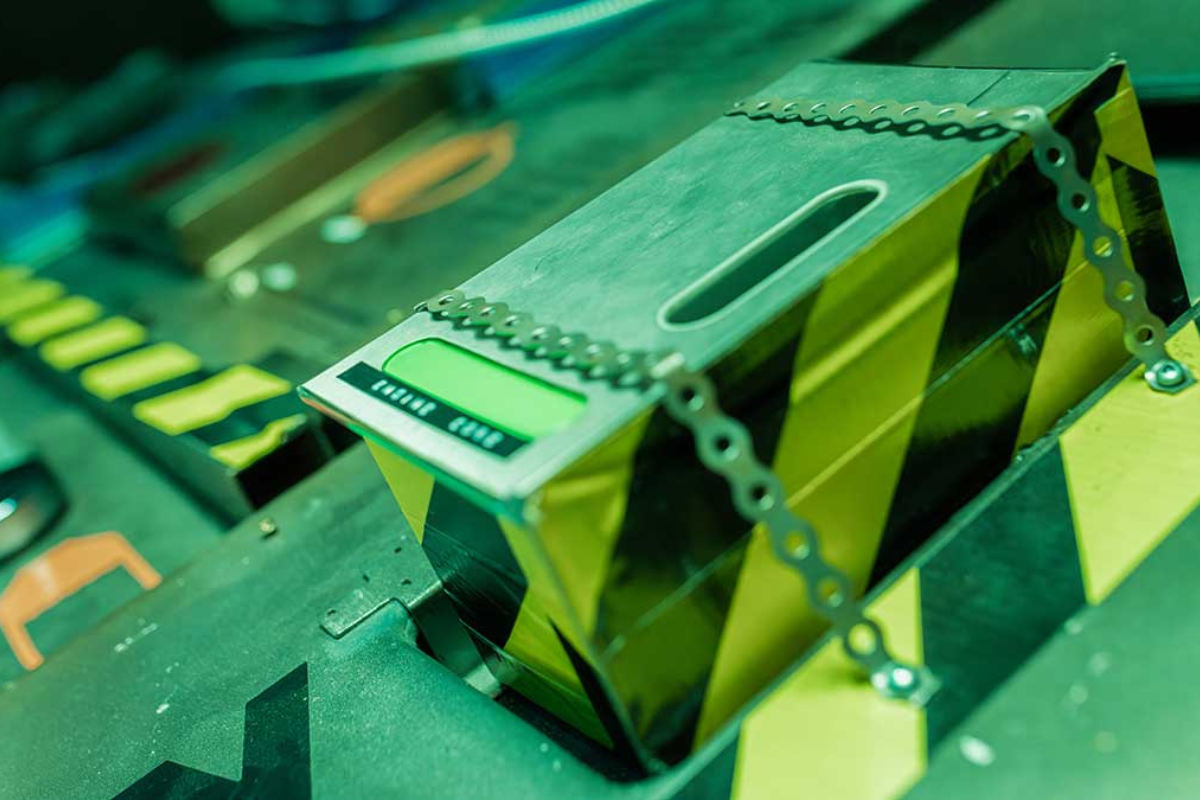 Metallic robot component with yellow hazard stripes, green display and decorative chain detail.