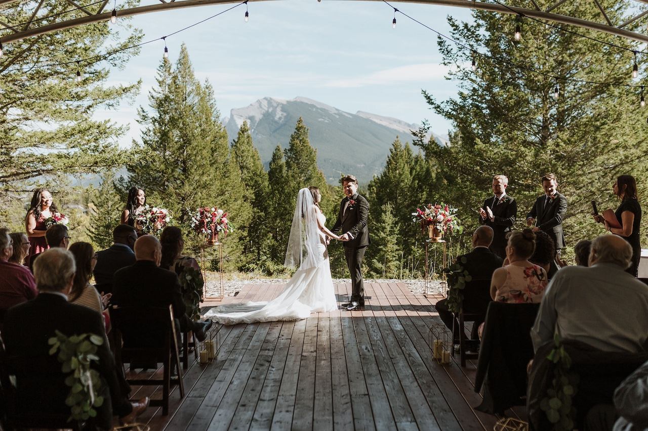 Outdoor ceremony on a wooden deck with forest and mountain backdrop
