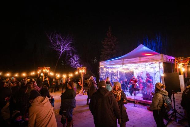 A crowd of people enjoy a live band in a winter night.