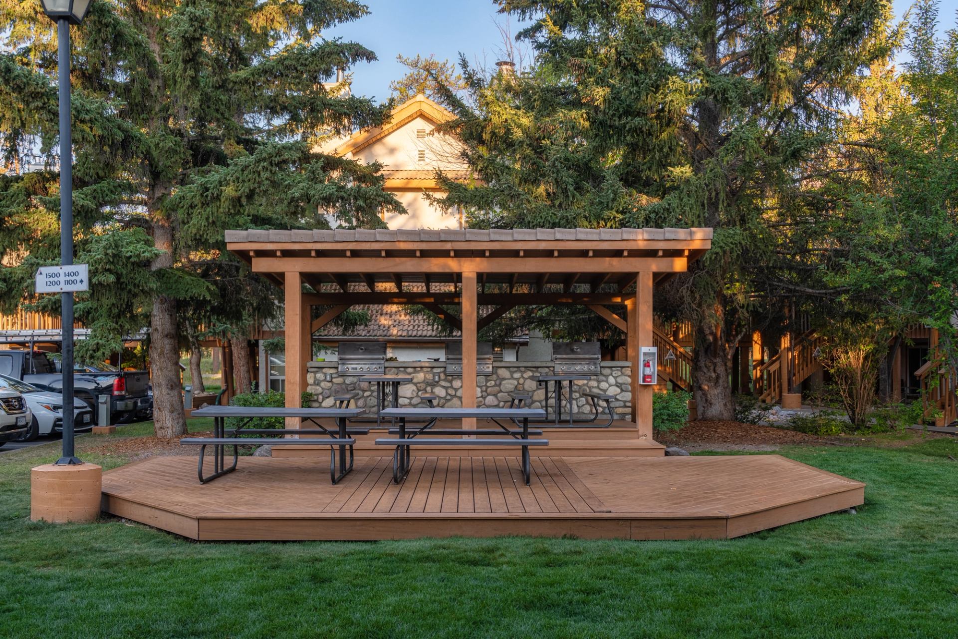 Small deck with two picnic tables, and 2 bbqs with a shade structure.