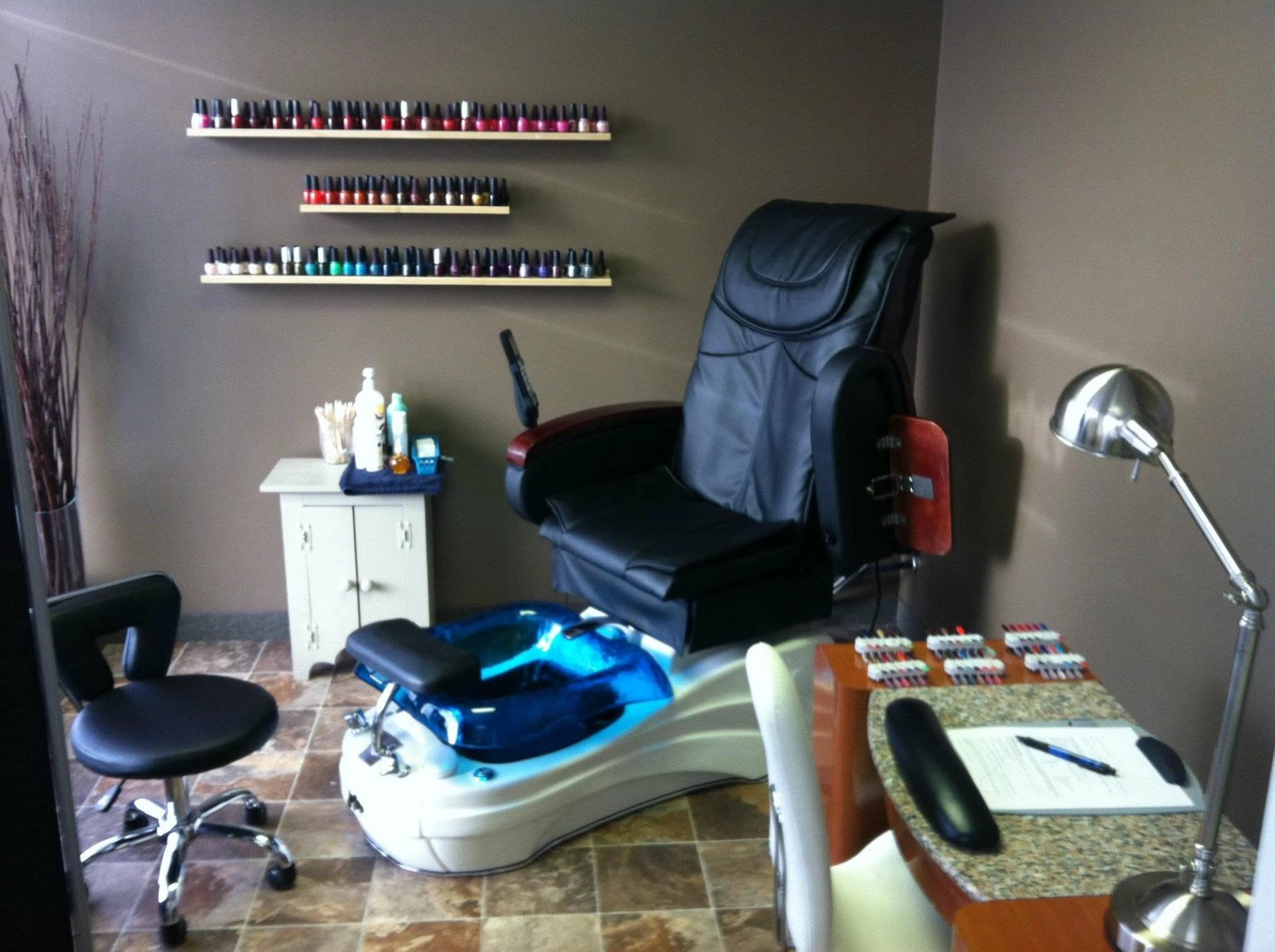 Pedicure spa chair with blue foot basin, nail polish shelves, and manicure station.