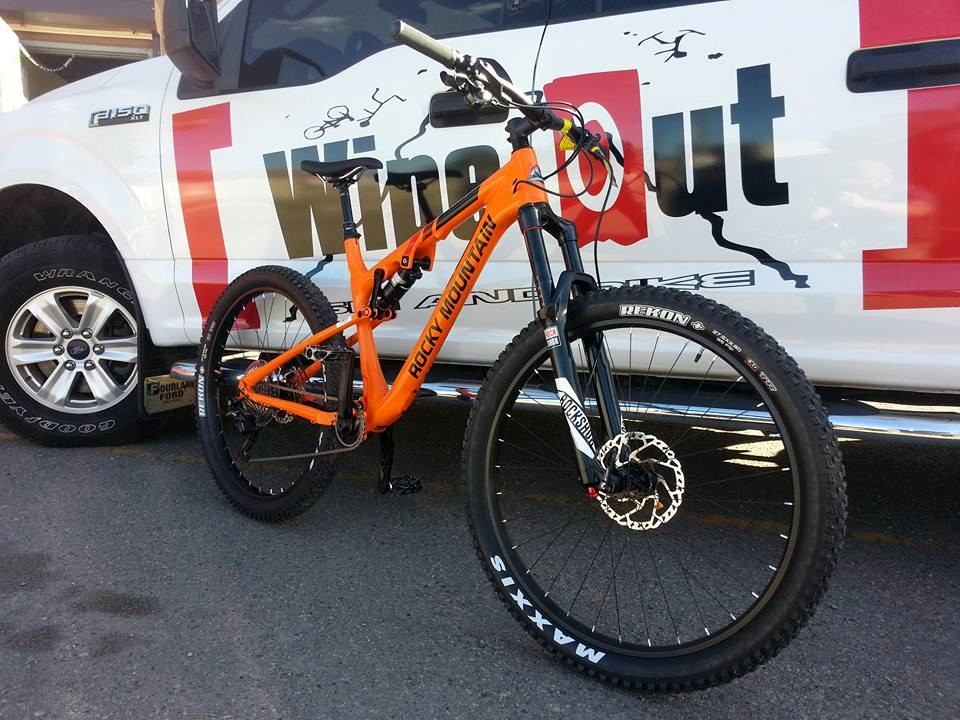 An orange mountain bike standing by a truck