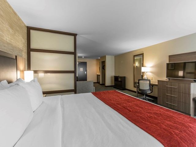 Spacious hotel room with king bed, desk, and modern furnishings.