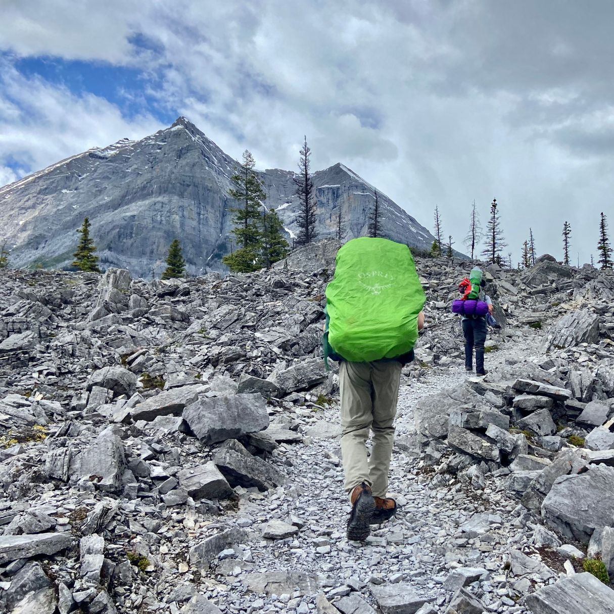 Two people backpacking up a hill.