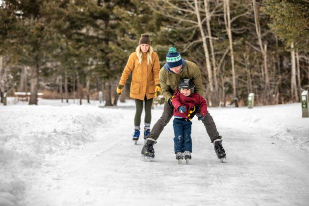 A family ice skating at an outdoor ice path in Cypress Hills Provincial Park.