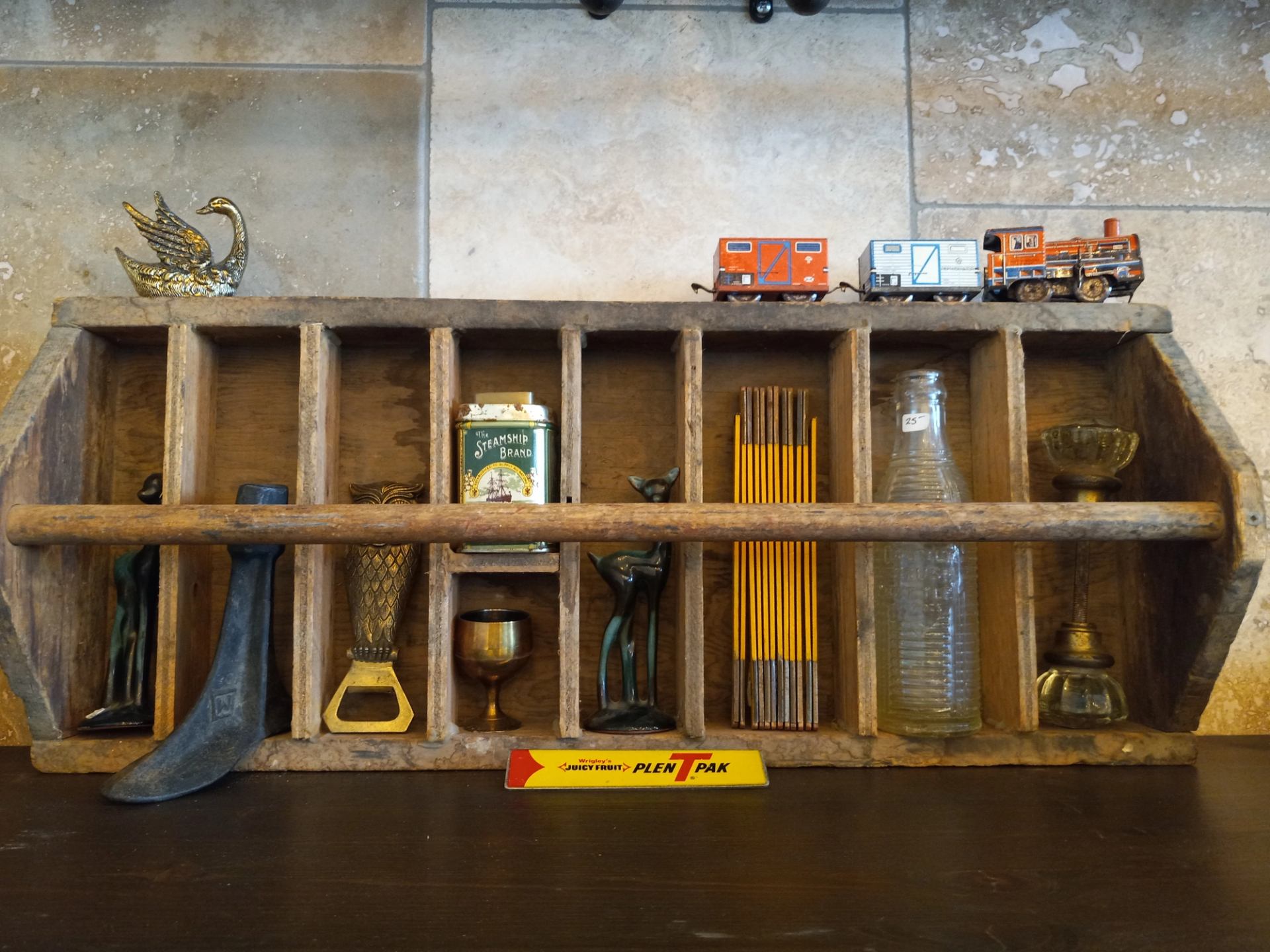 Rustic wooden shelf with vintage tools, pencils, glassware, and toy trains.