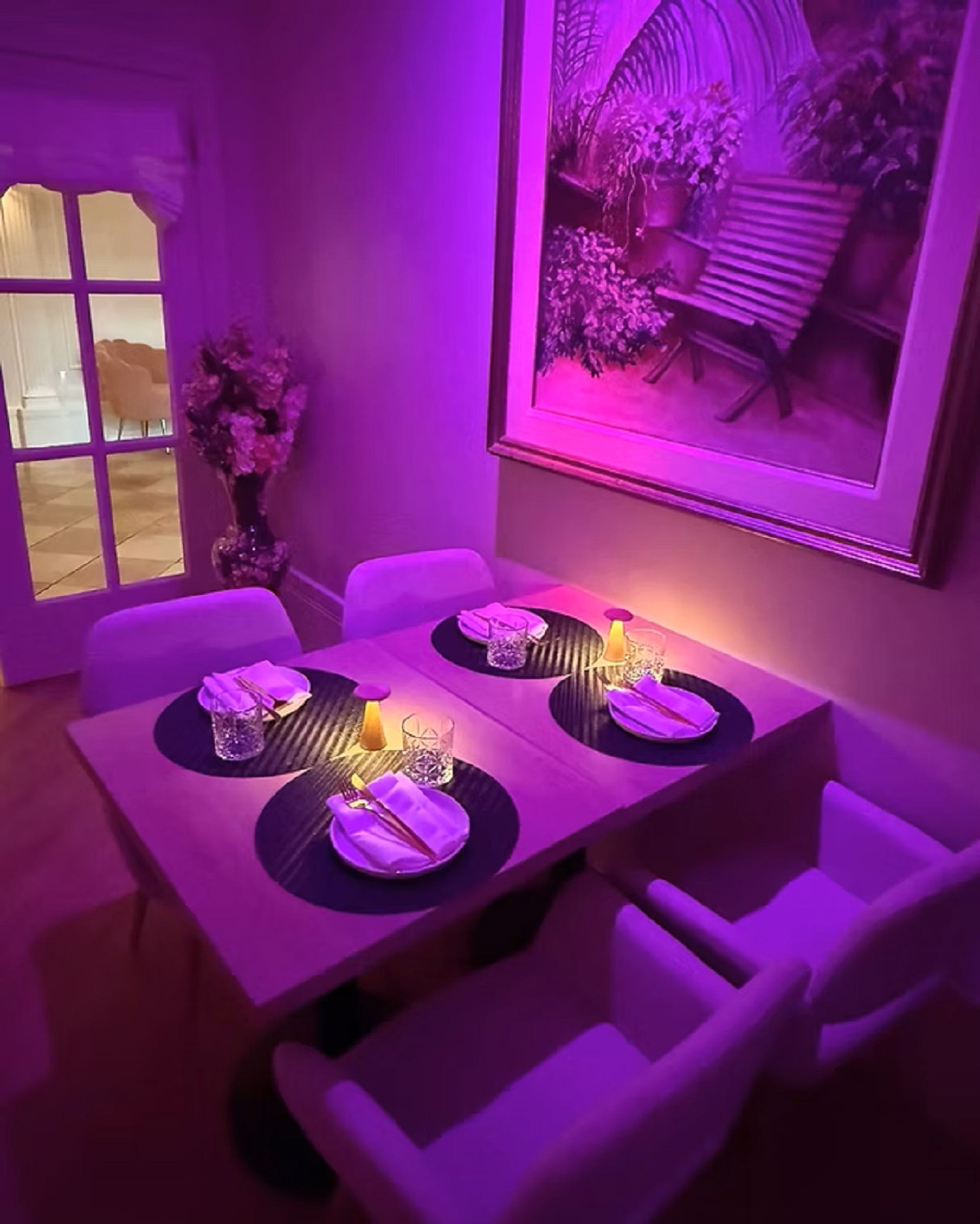 Candlelit dining table with plush chairs and purple ambient lighting inside Bungalow Club.