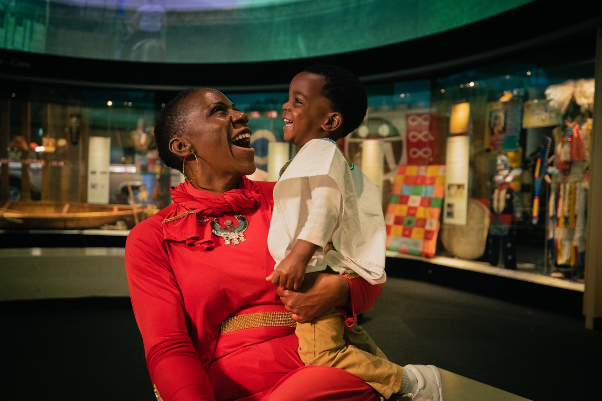 Adult holding a child while exploring a museum gallery.