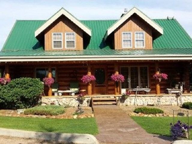 Rustic log cabin B&B with porch, flowers, and lush garden path.