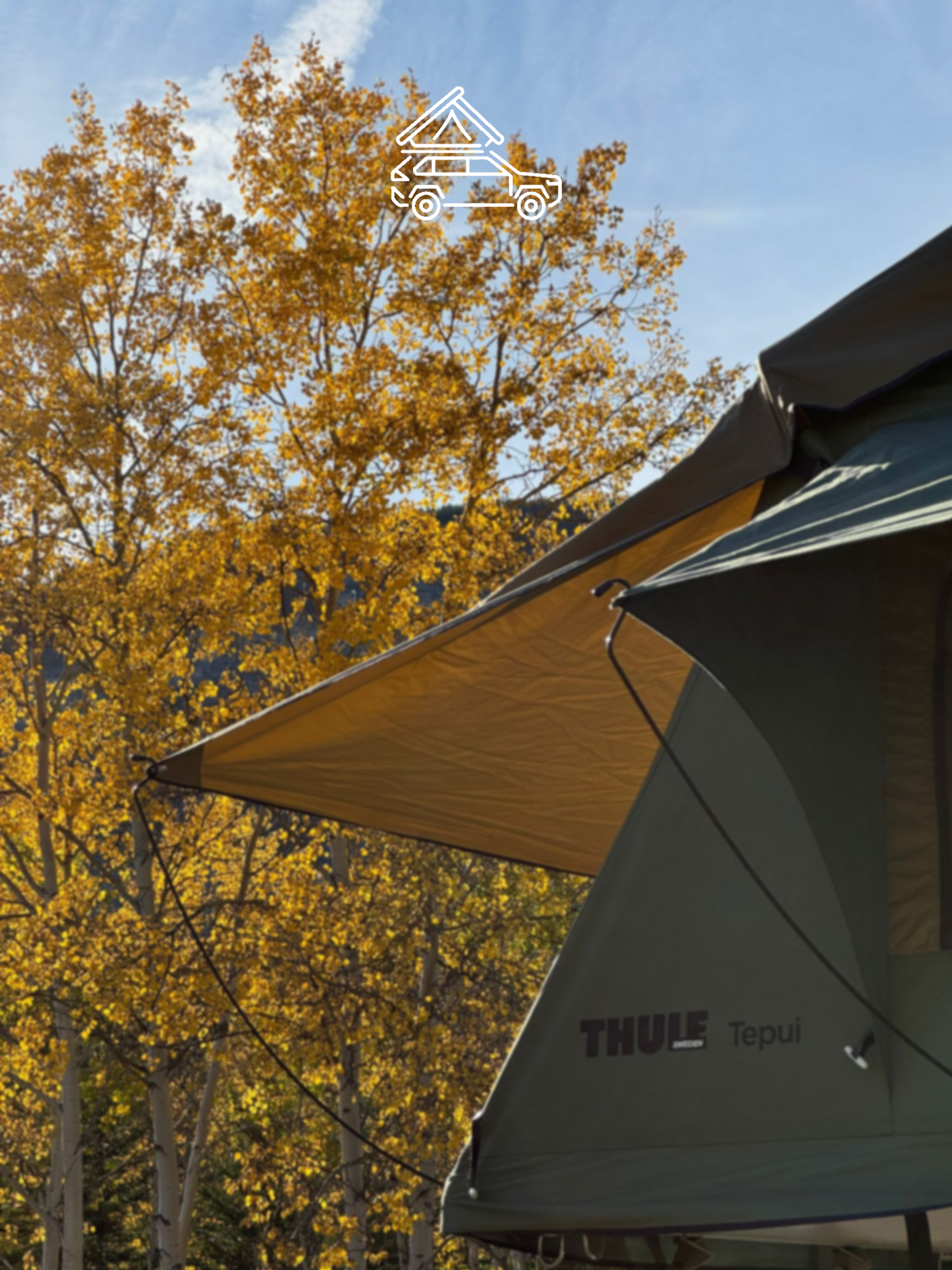 Thule Tepui rooftop tent with extended awning beside tall yellow-leaved trees.