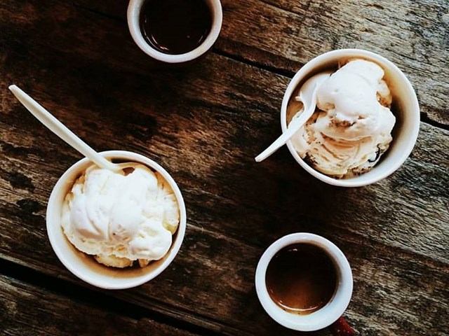 Two cups of ice cream with espresso shots on a rustic wooden table.