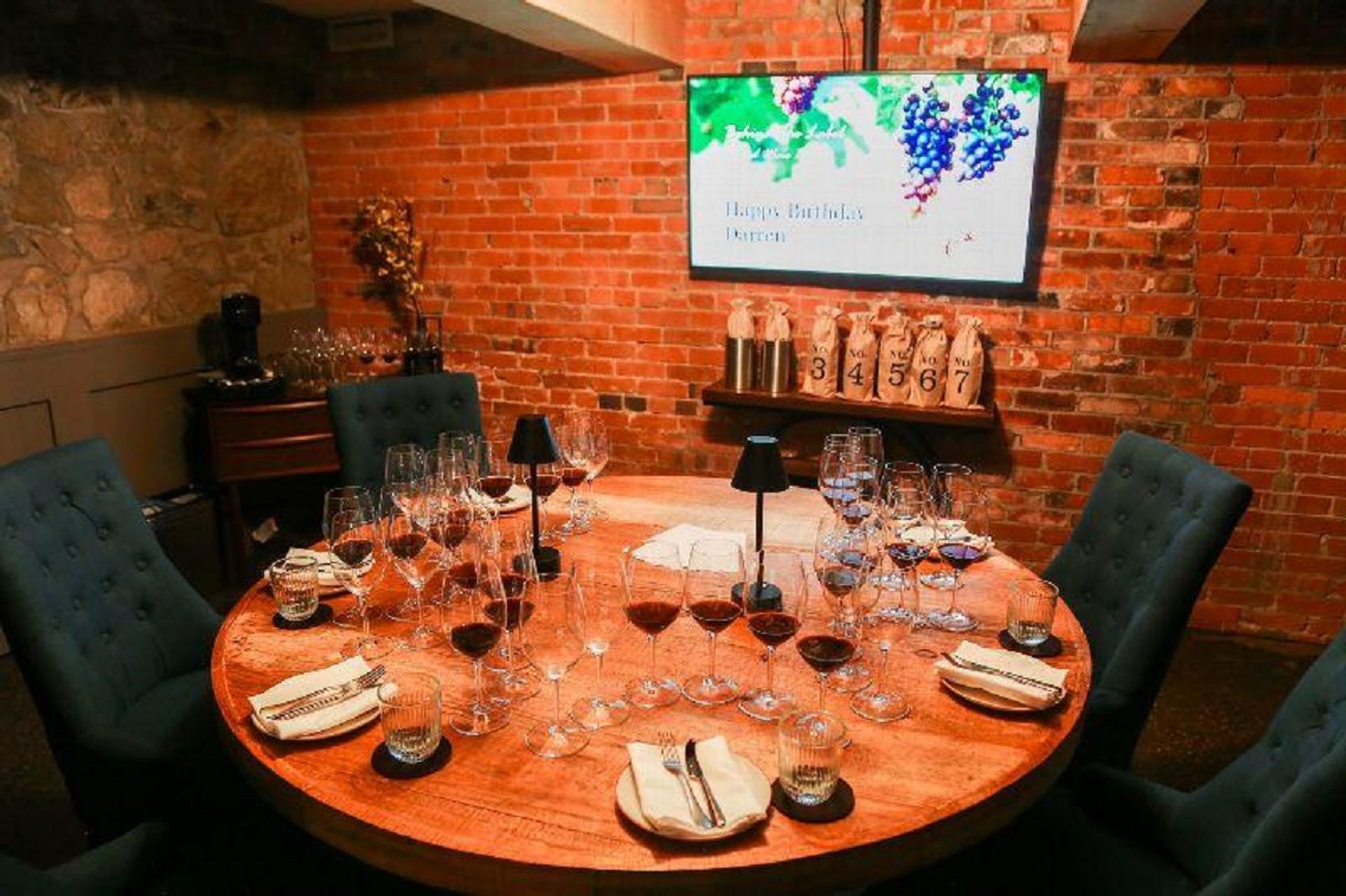 Private wine tasting room with a round table, wine glasses, candles, and exposed brick walls at CavernUs.