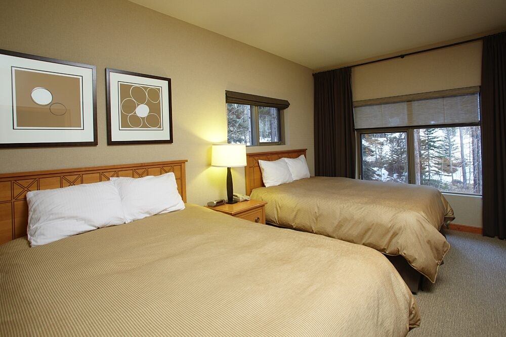 Guest room with two queen beds, bedside lamp, and framed artwork