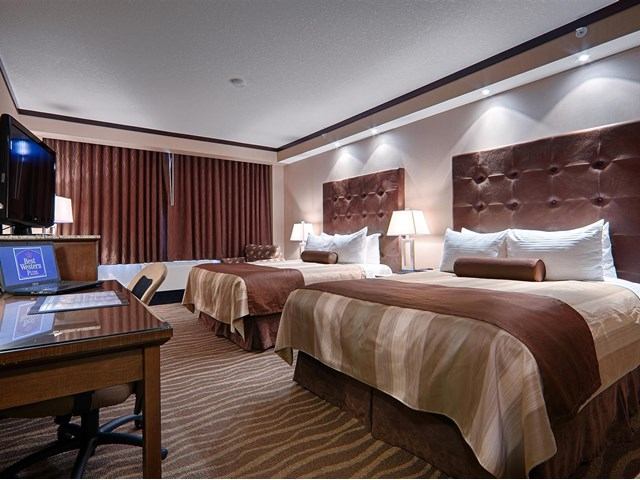Cozy hotel room with two beds, warm lighting, and modern furnishings.