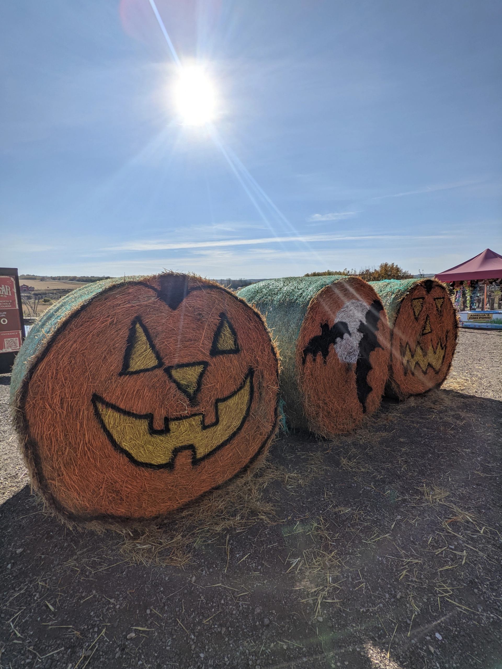 Three Halloween-themed hay bales with jack-o'-lanterns and ghost at Granary Road.