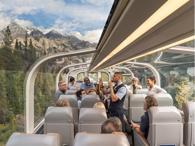 Passengers enjoy the mountain scenery through the expansive window of the train.