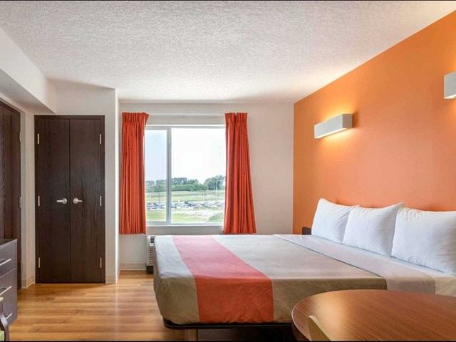 Compact kitchenette with fridge, microwave, sink, and dark wood cabinets.