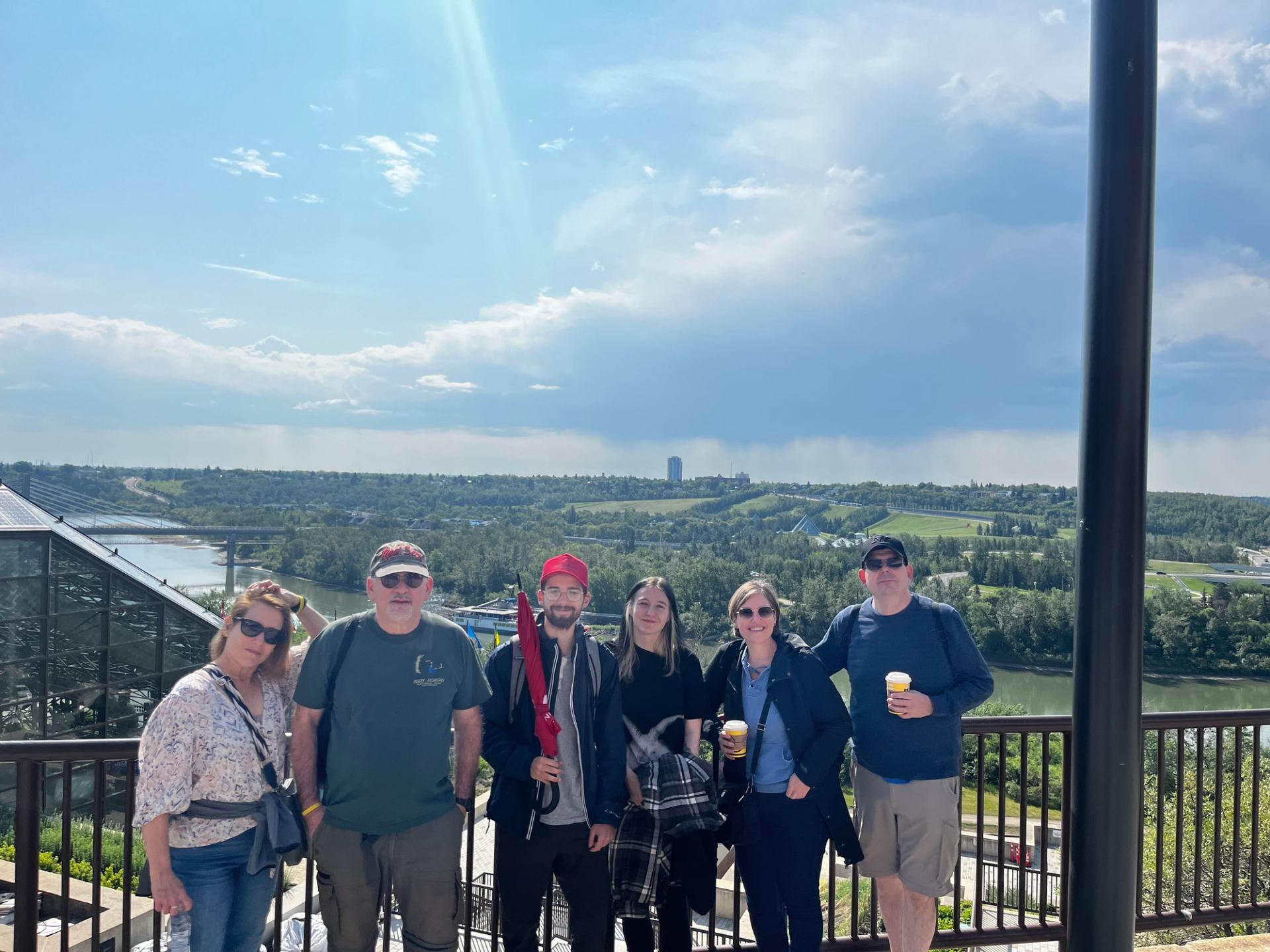 Group on scenic overlook with river, trees, and Edmonton skyline in the background.