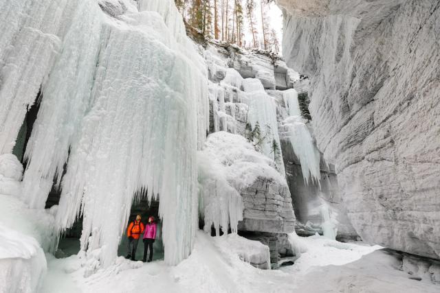 People exploring the frozen waterfalls at Maligne Canyon.